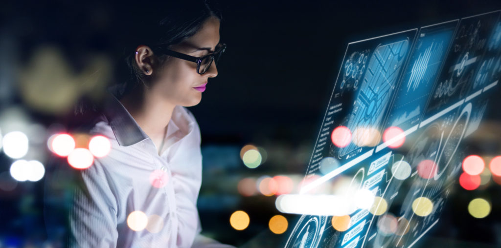 Businesswoman working at a futiristic digital interface screen with black background.