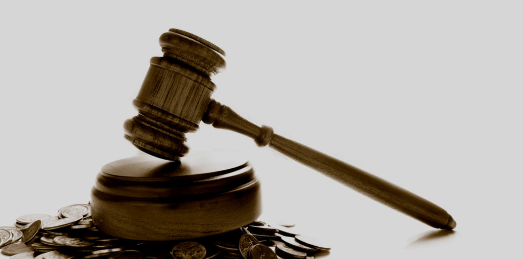 Judge's law gavel on a pile of coins, with white background.