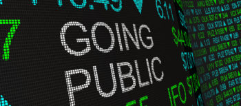 Digital text on a screen displaying stock prices and the words 'GOING PUBLIC'.