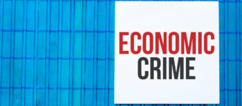 Blank note pad with text ECONOMIC CRIME on blue wooden background.with text ECONOMIC CRIME on blue wooden background