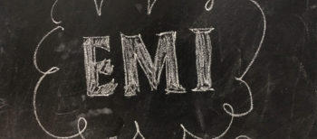 Blackboard with the letters EMI witten in white chalk.