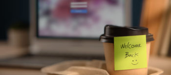 Close-up of a Welcome Back note on a takeaway coffee cup on an office desk. Concept of company coming back to life through administrative restoration.