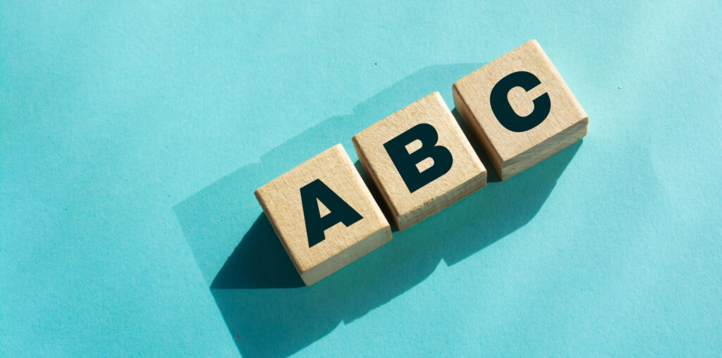 Three wooden blocks with A, B, C displayed on them against a light blue background, representing the the alphabet shares concept.