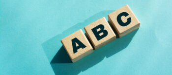 Three wooden blocks with A, B, C displayed on them against a light blue background, representing the the alphabet shares concept.