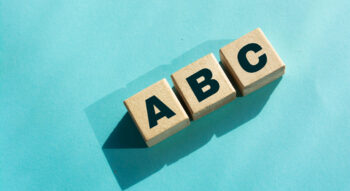 Three wooden blocks with A, B, C displayed on them against a light blue background, representing the the alphabet shares concept.