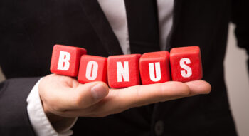 Businessman holding 5 red cubes spelling the word 'BONUS' on the palm of his hand.